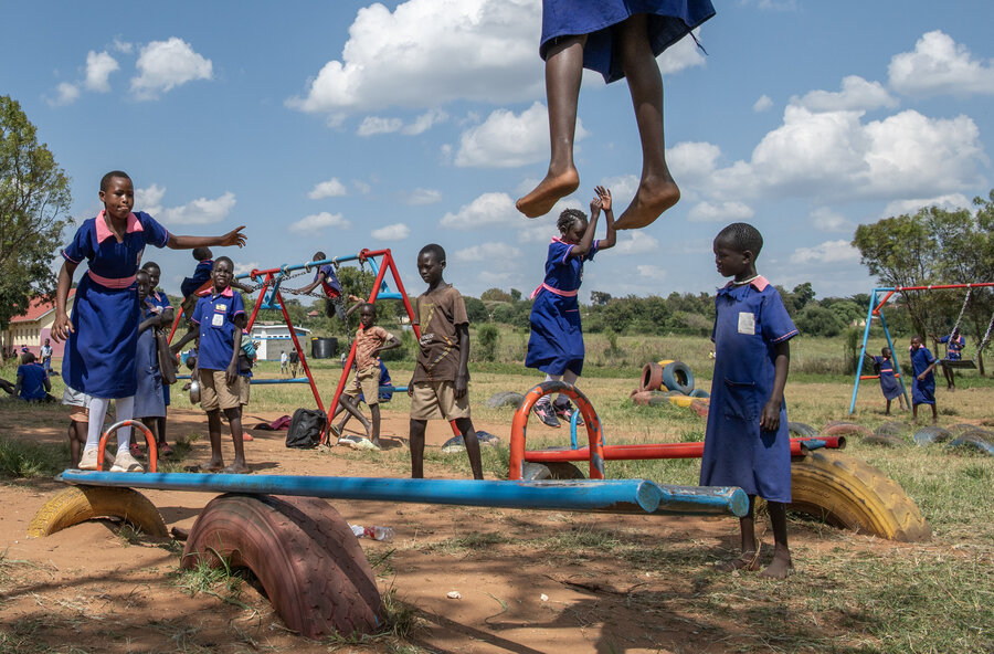 Young school children play outside, including on a makeshift seesaw. Photo: WFP/Alessandro Abbonizio