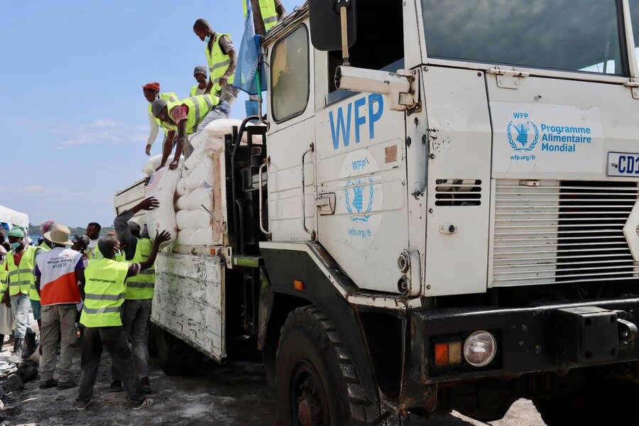 Workers wearing yellow vests unload bags of food from WFP trucks. Photo: WFP/Benjamin Anguandia