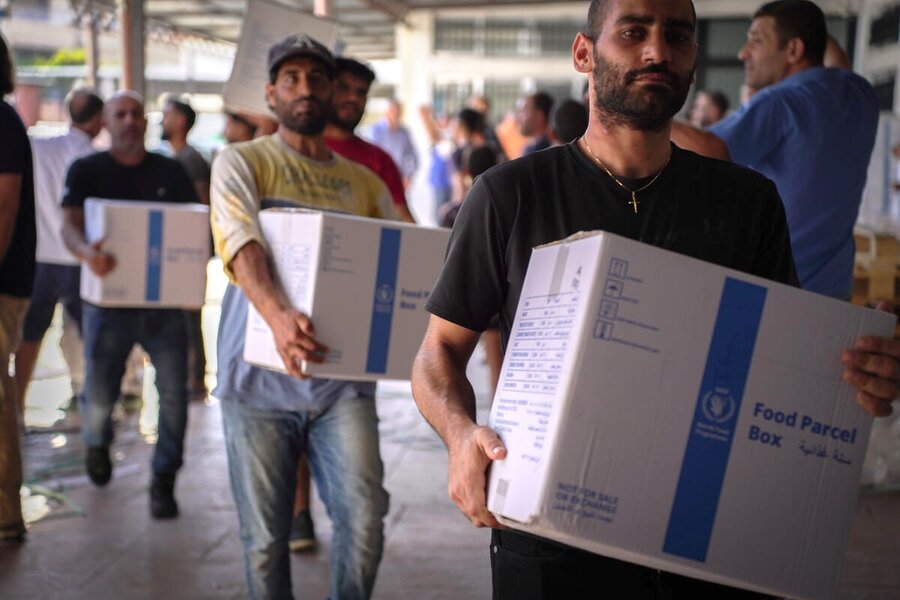 People carry WFP food parcels inside a distribution site, as organized assistance reaches households affected by ongoing conflict in area today safely.