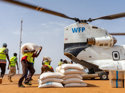 Staff unloading bags of food assistance from a WFP heavy-duty helicopter